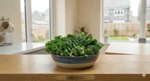 A close-up view of the same blue and cream ceramic bowl, now filled entirely with a fresh selection of bird-safe leafy greens including kale, spinach, and Swiss chard.
